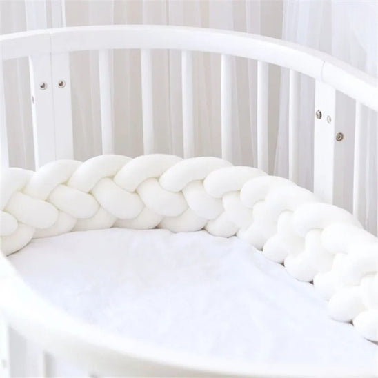 Tour de lit tressé blanc dans un lit à barreaux bébé