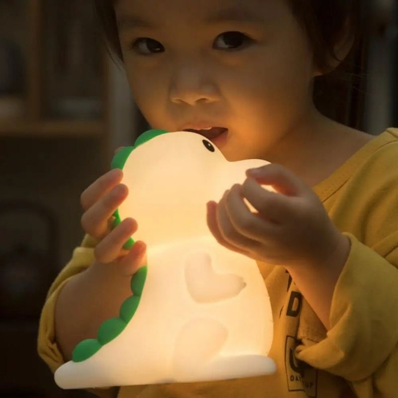 Petit garçon tenant une veilleuse bébé dinosaure lumineuse