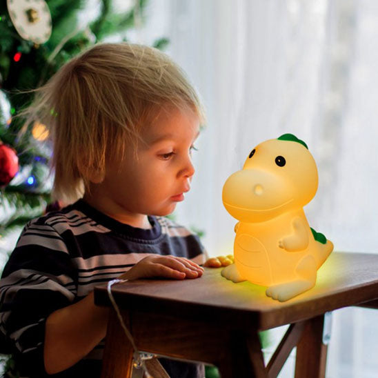 Petit garçon contemplant une veilleuse bébé dinosaure