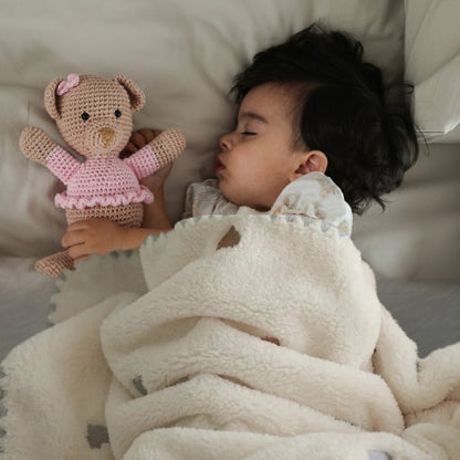 Couverture bébé motif cœurs brodés recouvrant bébé fille endormie