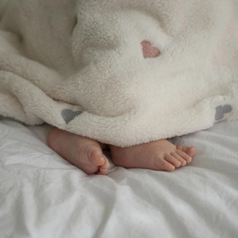 Pieds de bébé dépassant de couverture bébé polaire beige
