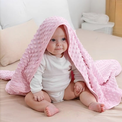 Couverture bébé fille rose en coton posée sur épaules