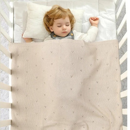 Couverture bebe en tricot beige enveloppant un bébé endormi
