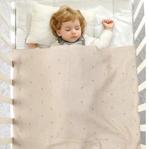 Couverture bebe en tricot beige enveloppant un bébé endormi