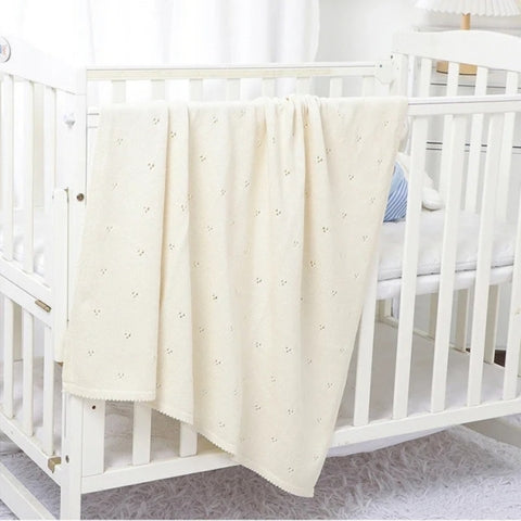 Couverture bebe tricot blanc sur lit à barreaux