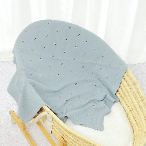 Couverture bebe tricot bleu posée dans un berceau