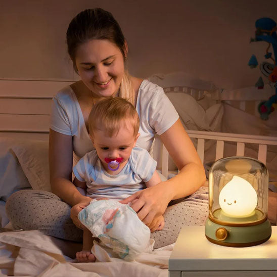 Maman changeant son enfant avec veilleuse bébé LED rechargeable allumée