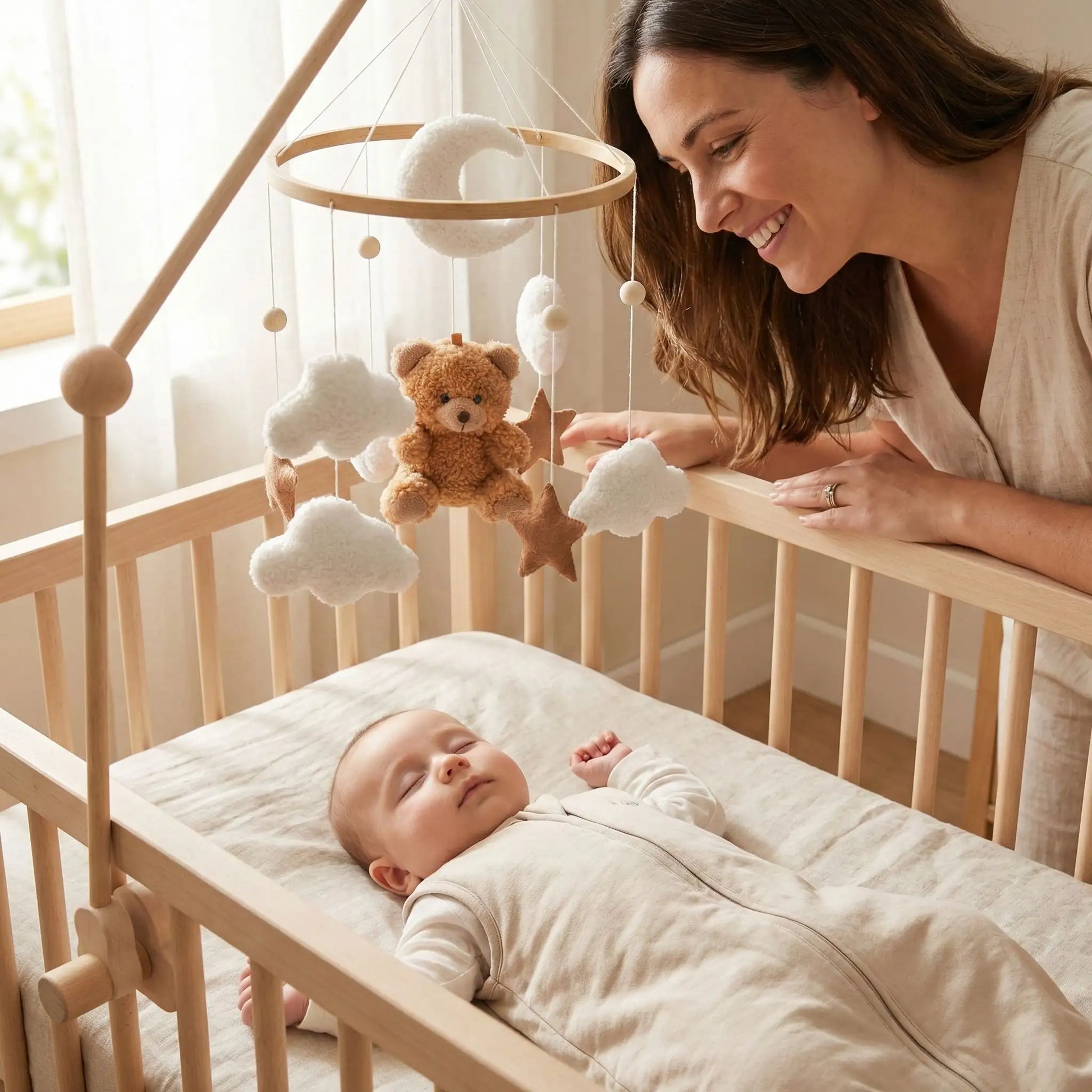 Maman souriante regardant bébé dormir sous mobile bebe