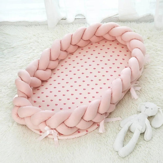 Reducteur de lit rose posé sur tapis avec doudou lapin