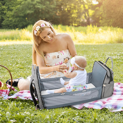 Bébé assis dans le sac a langer-lit au parc 
