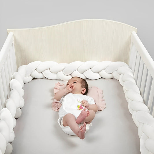 Bébé réveillé dans son lit à barreaux protégé par un tour de lit tressé blanc universel