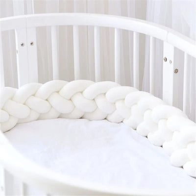 Tour de lit tressé blanc dans un lit à barreaux bébé