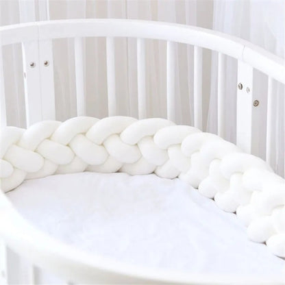 Tour de lit tressé blanc dans un lit à barreaux bébé