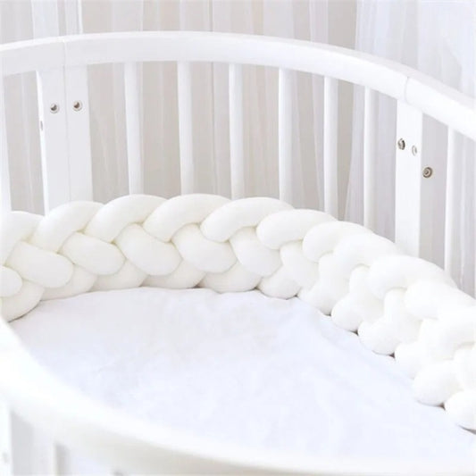 Tour de lit tressé blanc dans un lit à barreaux bébé