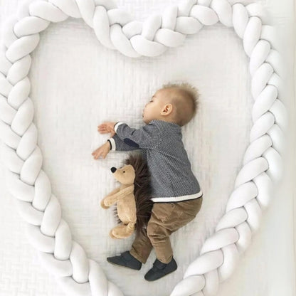 Bébé dort paisiblement dans un lit sécurisé par un tour de lit tressé blanc délimitant son espace de sommeil