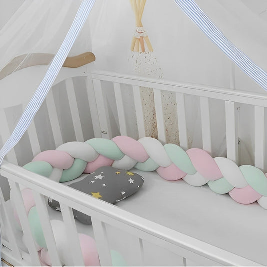 Tresse de lit bébé rose vert blanc installée dans lit barreaux