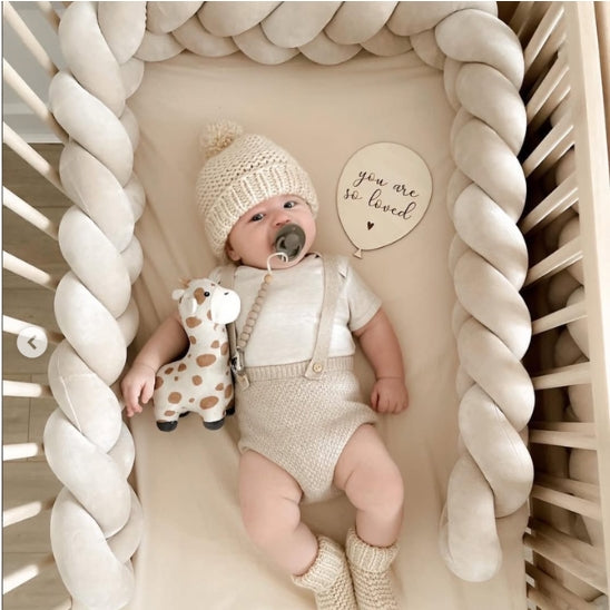 Tresse de lit bébé velours crème dans lit barreaux avec bébé