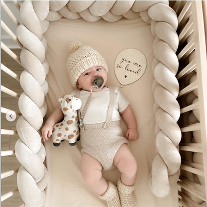 Tresse de lit bébé velours crème dans lit barreaux avec bébé