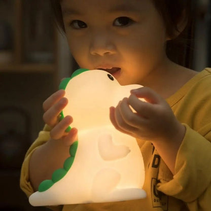Petit garçon tenant une veilleuse bébé dinosaure lumineuse