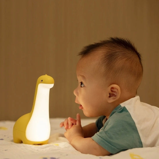 Veilleuse bebe tactile dinosaure jaune éclairant bébé sur le ventre