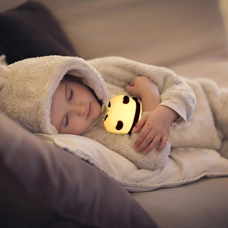 Veilleuse de nuit panda dans les bras d'un enfant endormi